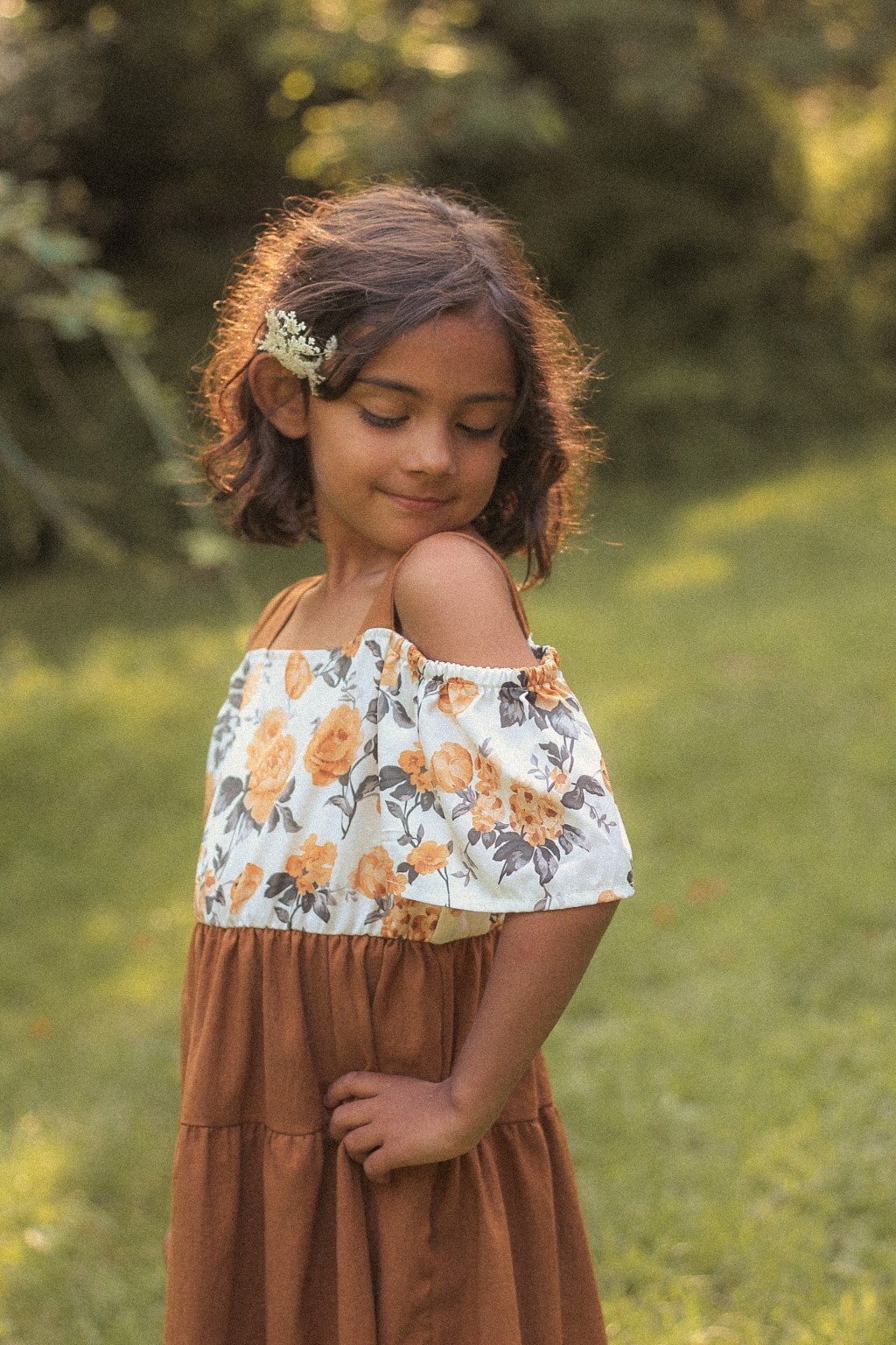 Child looking down in a rust and floral dress